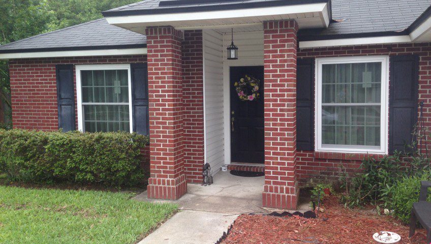 A brick house with a porch and door.