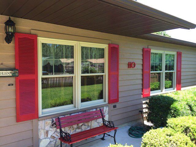 A red bench sitting in front of a house.